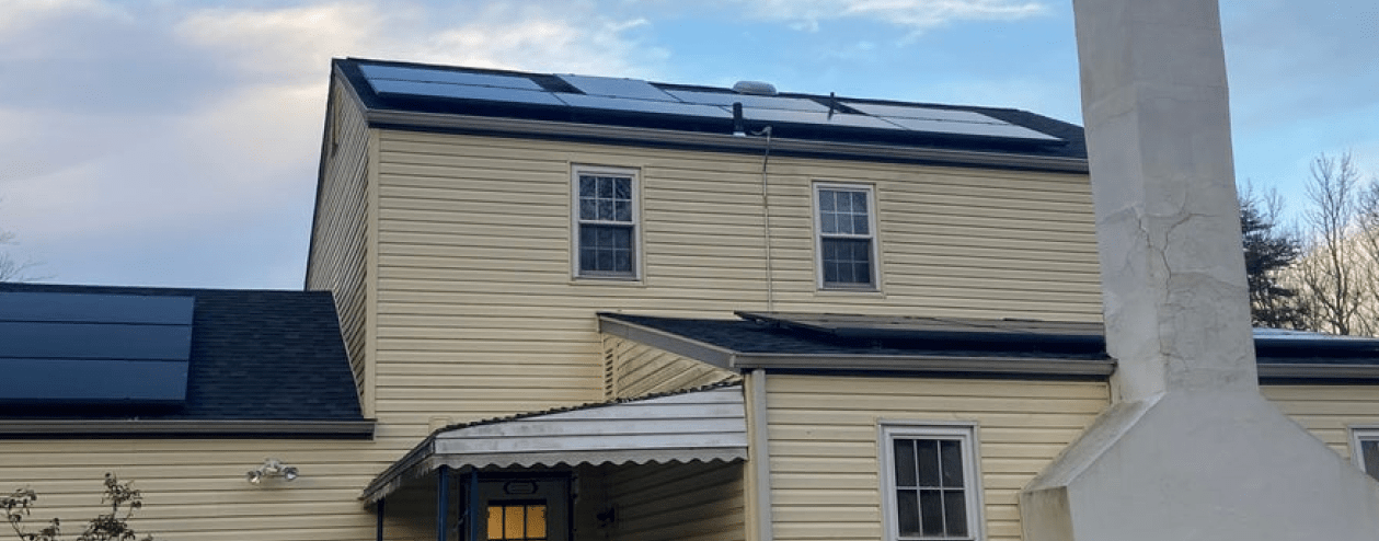 A backyard view of a home with rooftop solar panels Reply