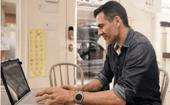 Man interacting with a laptop in his kitchen looking at Solar Loan Agreement