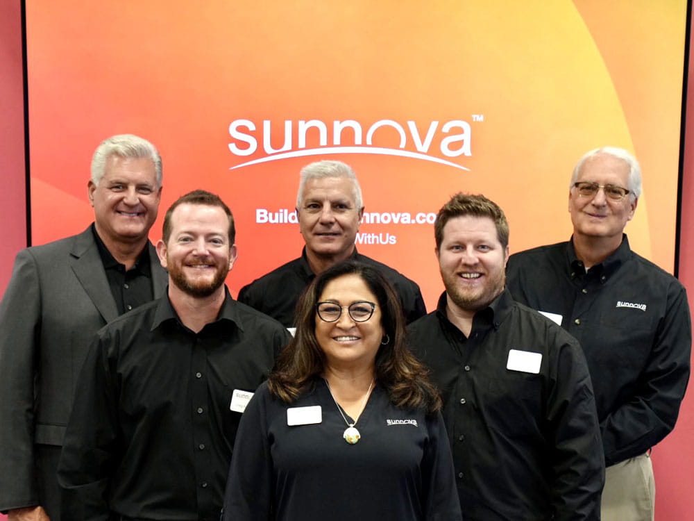 a group of people standing in a row with Sunnova logo in background