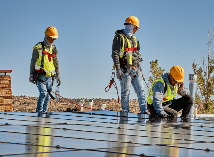 three construction workers standing on solar panels