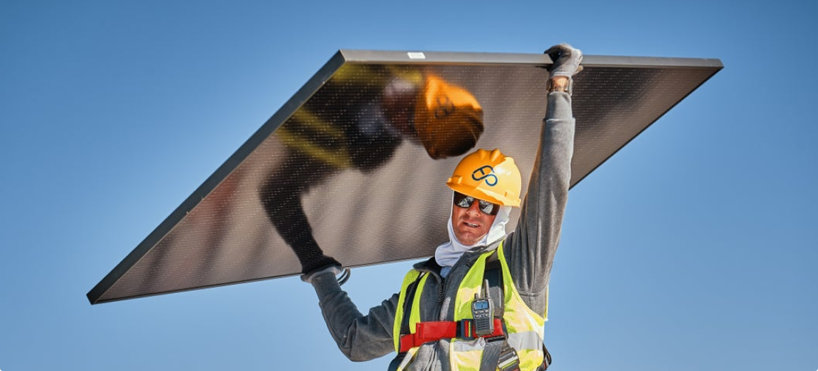 construction worker carrying a solar panel